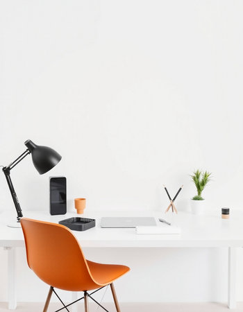 Mockup of workspace with orange armchair, laptop, coffee cup, stationery and copy space on white wallの写真素材