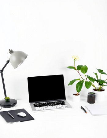 Modern workspace with laptop, coffee cup, plant, notebook and lamp on white background.の写真素材