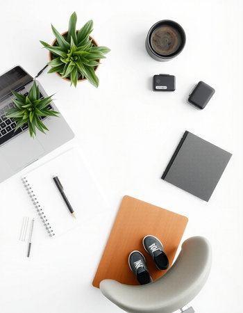 Top view of modern workplace with laptop, coffee cup, stationery and plant on white backgroundの写真素材