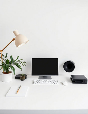 Minimalistic workspace with blank computer screen, stationery, coffee cup and plant on white table.の写真素材