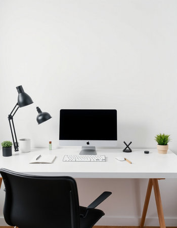 workplace with computer, lamp and stationery on white wall backgroundの写真素材