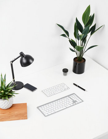 Minimalistic workplace with computer, mobile phone, coffee cup and plant on white table