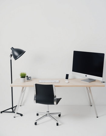 workplace with computer, lamp and table on white wall in officeの写真素材