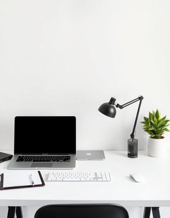 Modern workplace with blank screen laptop and office supplies on white desk.の写真素材