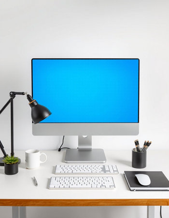 Modern workspace with computer, keyboard, mouse, lamp and coffee cup.