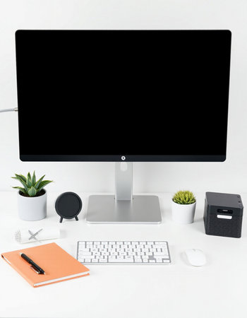 Computer with blank screen, keyboard and office supplies on white desk.