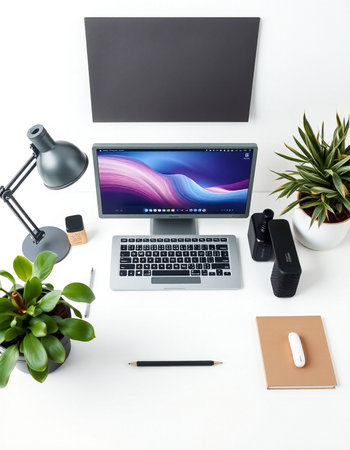 Top view of modern workspace with laptop, smartphone, stationery and green plant on white backgroundの写真素材