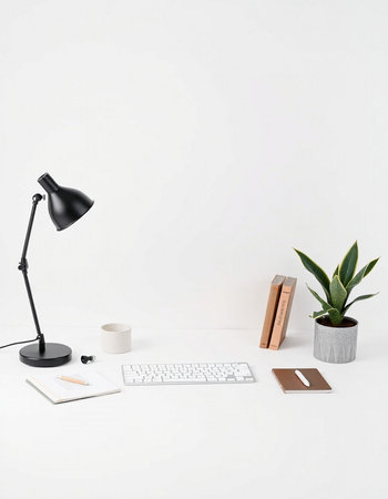 White office desk with keyboard, coffee cup, books, plant and black lamp. Workplace conceptの写真素材