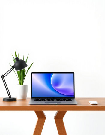 Laptop on wooden table with lamp and plant on white wall background