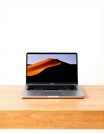 Laptop on a wooden table with a white wall in the background