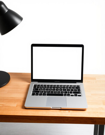 Laptop with blank screen on wooden table and lamp on white wall background