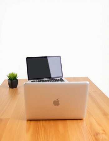 Laptop computer on wooden desk with white wall background