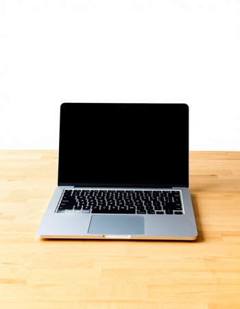 Laptop with blank black screen on wood table and white wall background