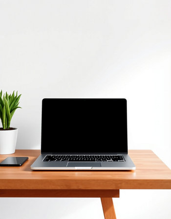 Laptop with blank screen on wooden table and white wall background.