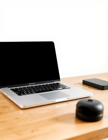 Laptop computer and mouse on a wooden table with white wall background