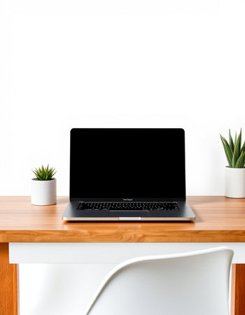 Laptop with blank screen on wooden table and white wall background.