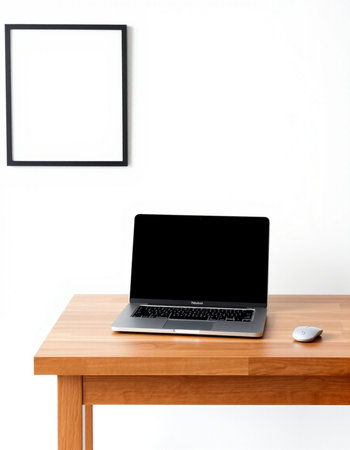 Laptop with blank screen on wooden table and white wall background.