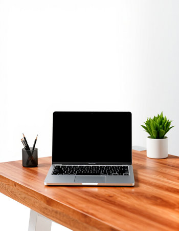 Laptop with blank screen on wooden table and white wall background.