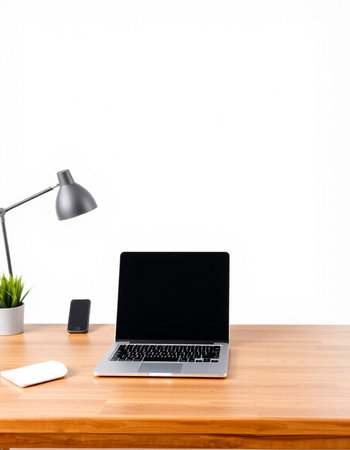 Laptop with blank screen on wooden desk and white wall background.