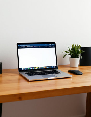 Laptop with blank screen on wooden table and white wall background.
