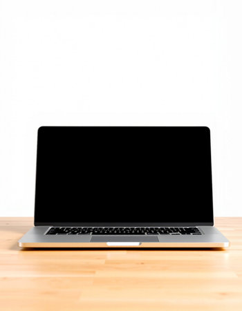 Laptop with blank screen on wood table and white wall background.