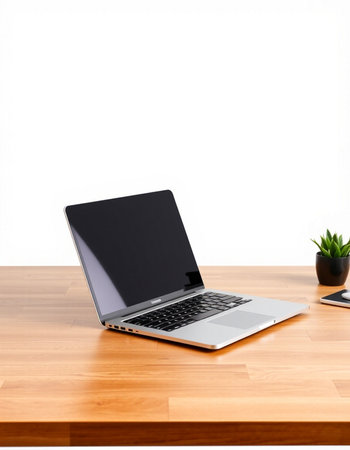 Laptop on a wooden table with a white wall in the background