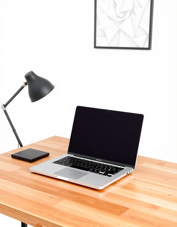 Laptop on wooden desk and lamp on white wall background, stock photo