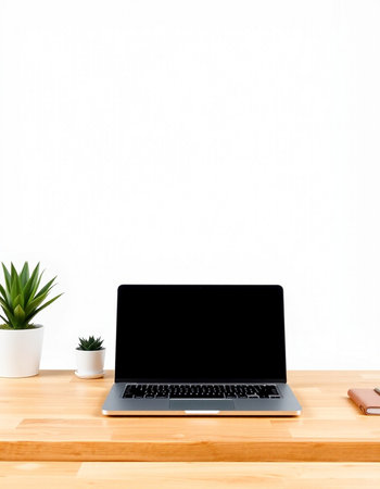 Laptop with blank screen on wooden desk and white wall background.