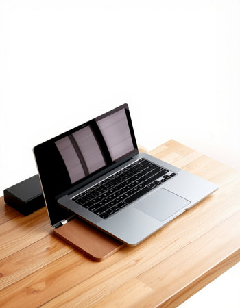 Laptop on a wooden table against a white wall with copy space