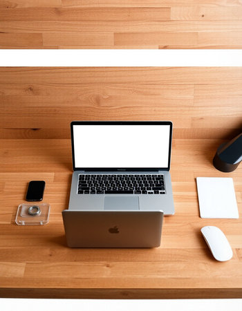 Laptop with blank screen and office supplies on the wooden desk.