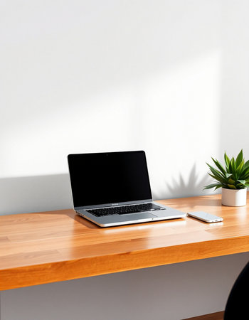 Laptop with blank screen on wooden table and white wall background.の写真素材
