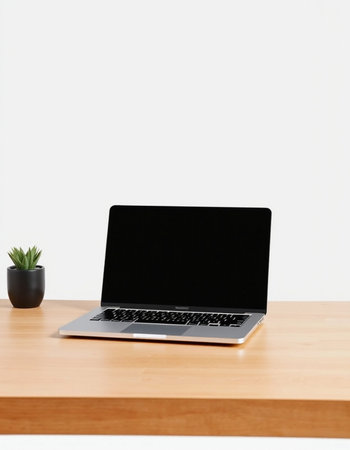 Laptop on a wooden table with a white wall in the background