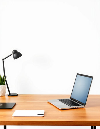 Modern workplace with laptop on wooden table and white wall background.