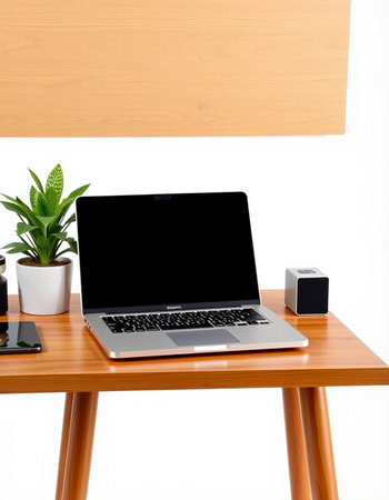 Laptop with blank screen on wooden table and white wall background.