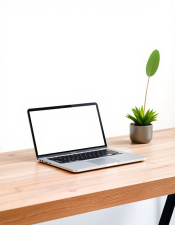 Laptop with blank screen on wooden table and white wall background.