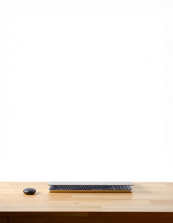 Wooden desk with black keyboard and mouse on white wall background.