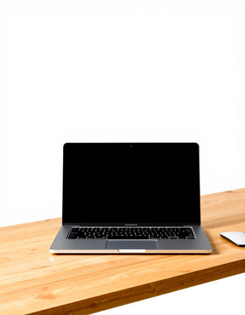 Laptop with blank screen on wooden table and white wall background.