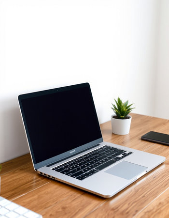 Laptop with blank screen on wooden desk in office, stock photo