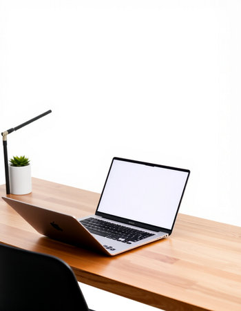 Laptop with blank screen on wooden table and white wall background.
