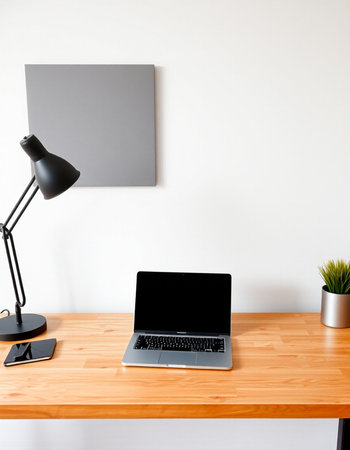 Modern workspace with laptop on wooden table and lamp on white wall background