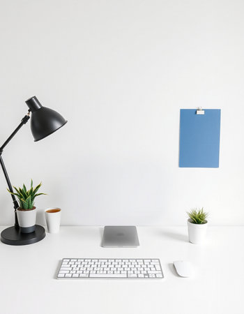 White office desk with computer, keyboard, mouse, coffee cup, plant and blue clipboardの写真素材