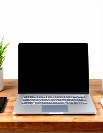 Laptop with blank screen on wooden table and white wall background.