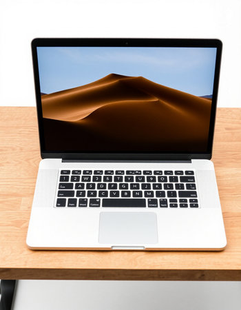laptop on wooden desk with dunes and blue sky in background
