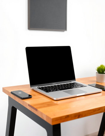 Laptop computer with blank screen on wooden table in modern office.