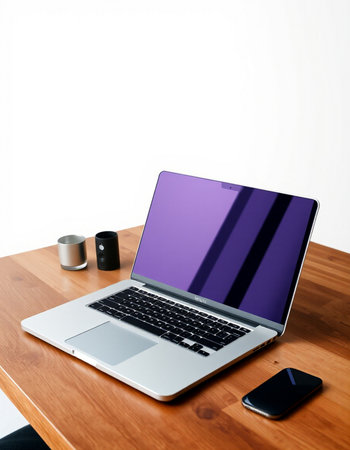 Laptop on wooden desk with smart phone and speaker on white background