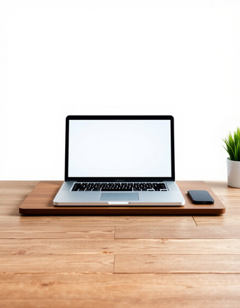 Laptop with blank screen on wooden table and white wall background.