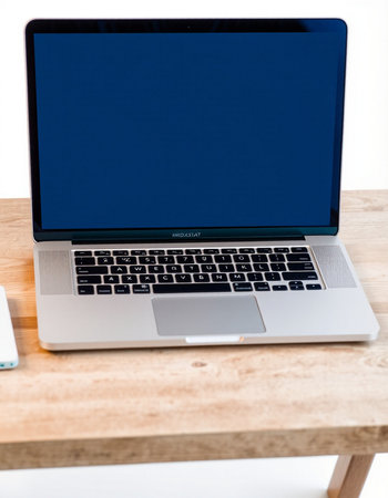 Laptop with blank screen on wooden table in office, stock photo