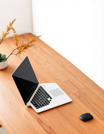 Laptop on a wooden table with a white wall in the background