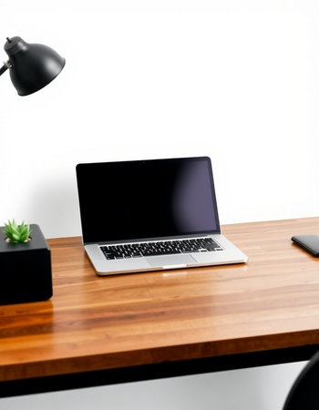 Laptop computer on wooden desk with white wall background, stock photo