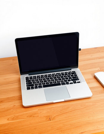 Laptop on wooden table with white wall in the background, stock photo